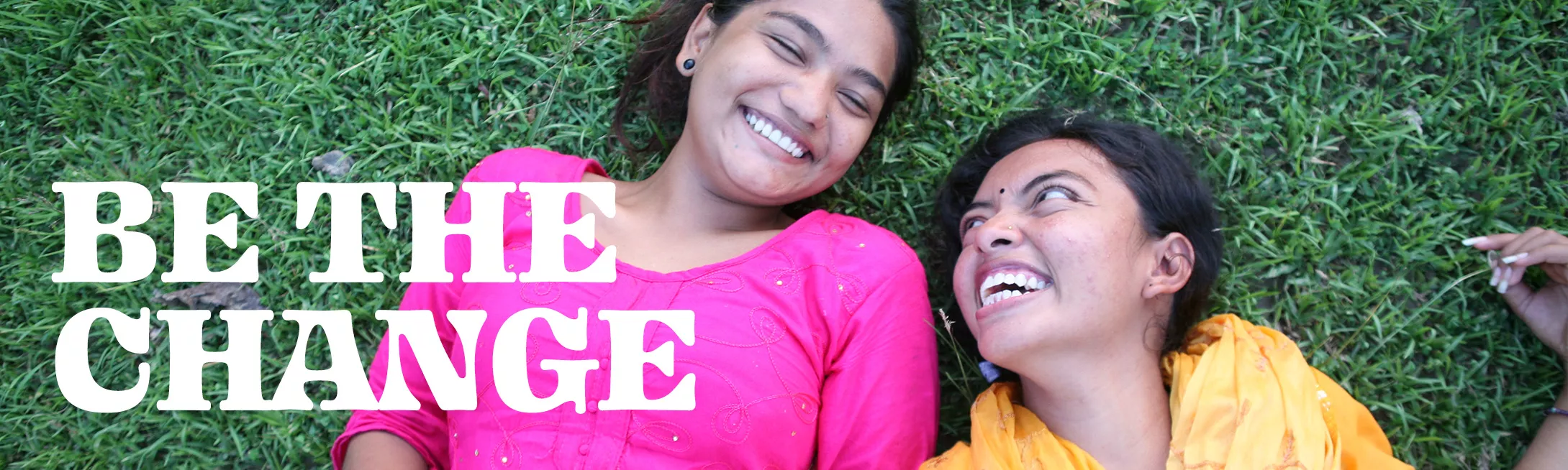 2 girls smiling at each other with text "Be The Change"