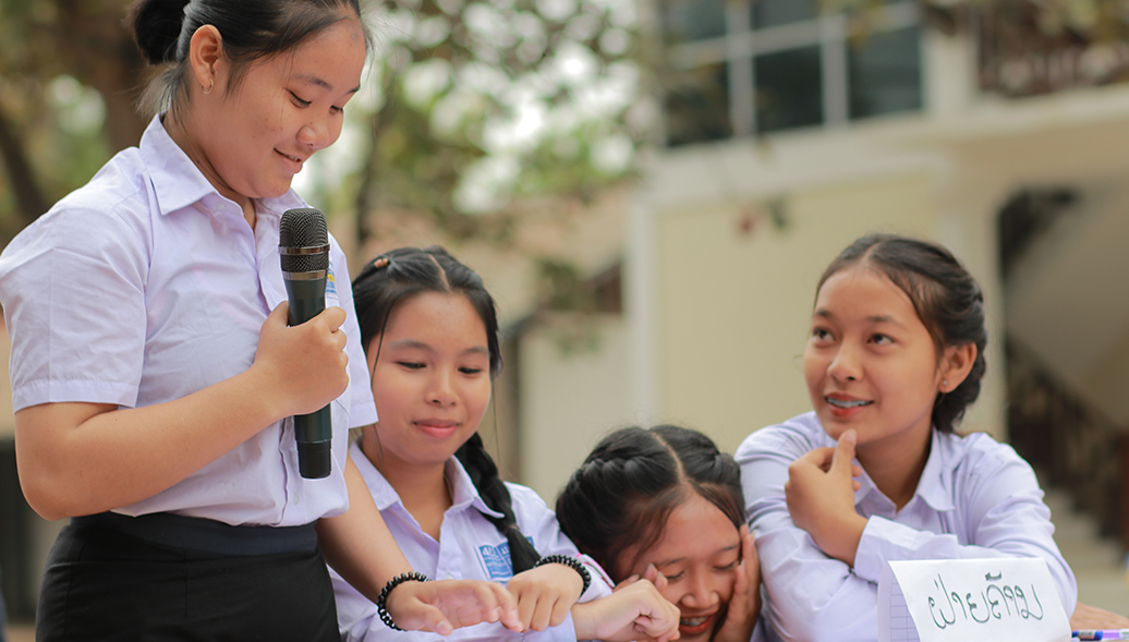 Group of Vietnamese girls sitting at a table outside making a presentation with a microphone