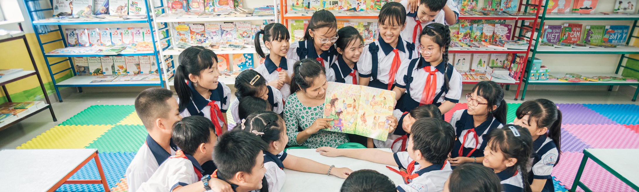 A reader reads aloud to primary school students in a colorful library in Vietnam. 