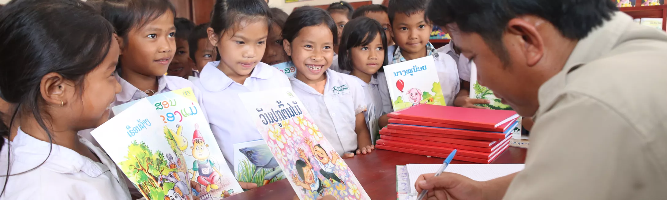 Students in a school library in Laos line up to check out storybooks. 