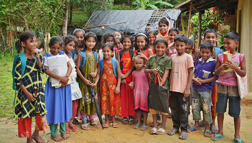 Large group of kids standing outside in Bangladesh with backpacks smiling