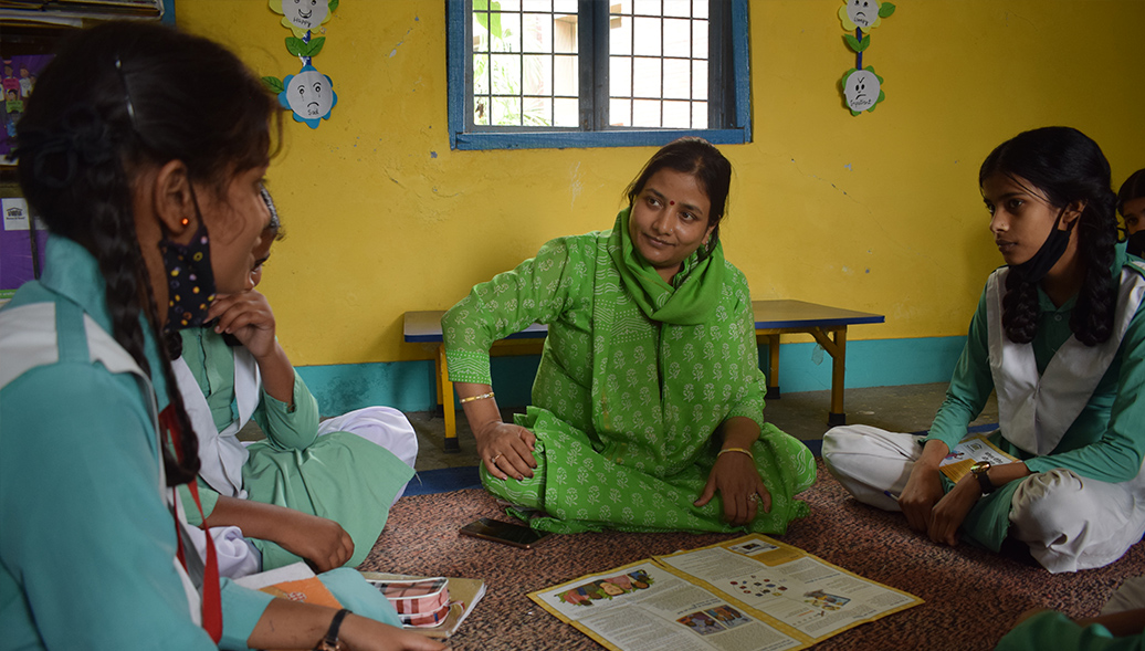 Group of Indian girls sitting in circle in a classroom with books in front of them