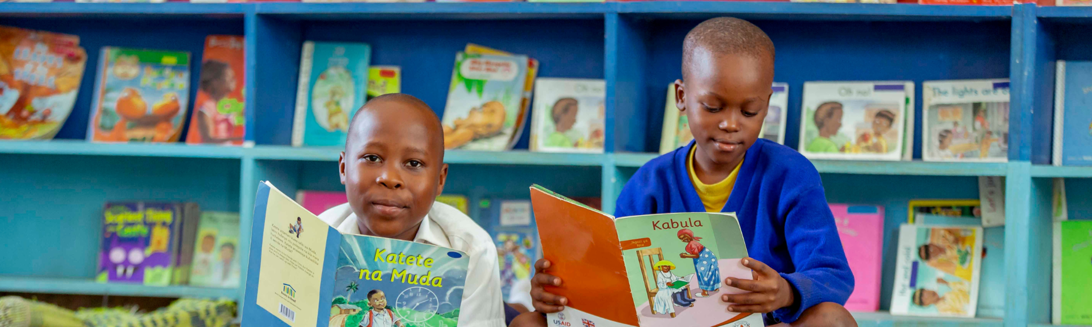 2 South African kids smiling and reading on the floor of a colorful library