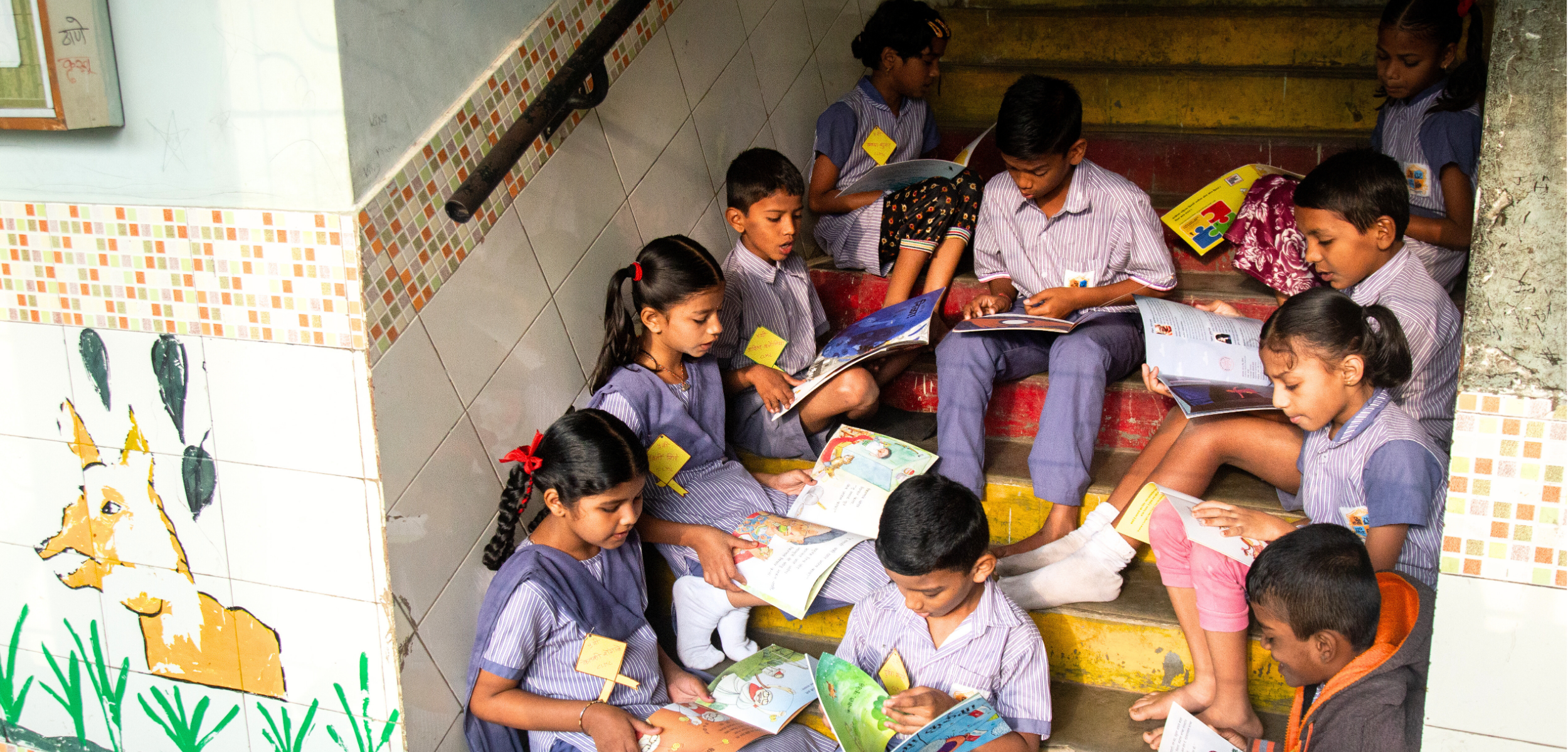 Promoting book use in a digital world in a primary school in India where children are seen reading books in a colorful school stairwell.