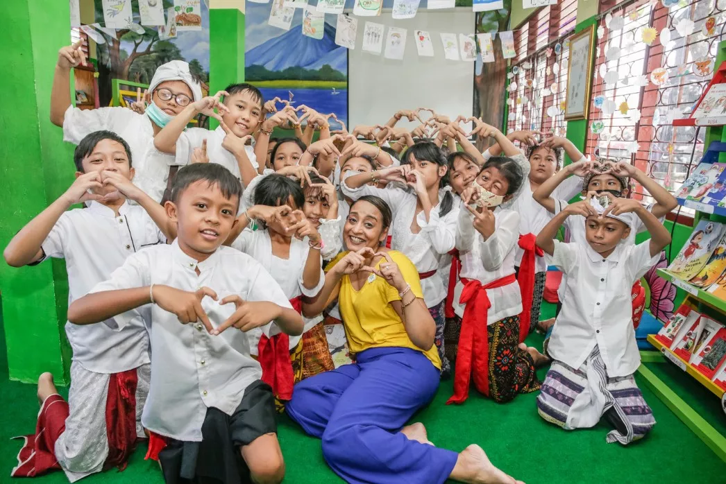 Dr. Geetha Murali posing with a group of Indonesian students in a library, all making heart sign with their hands.